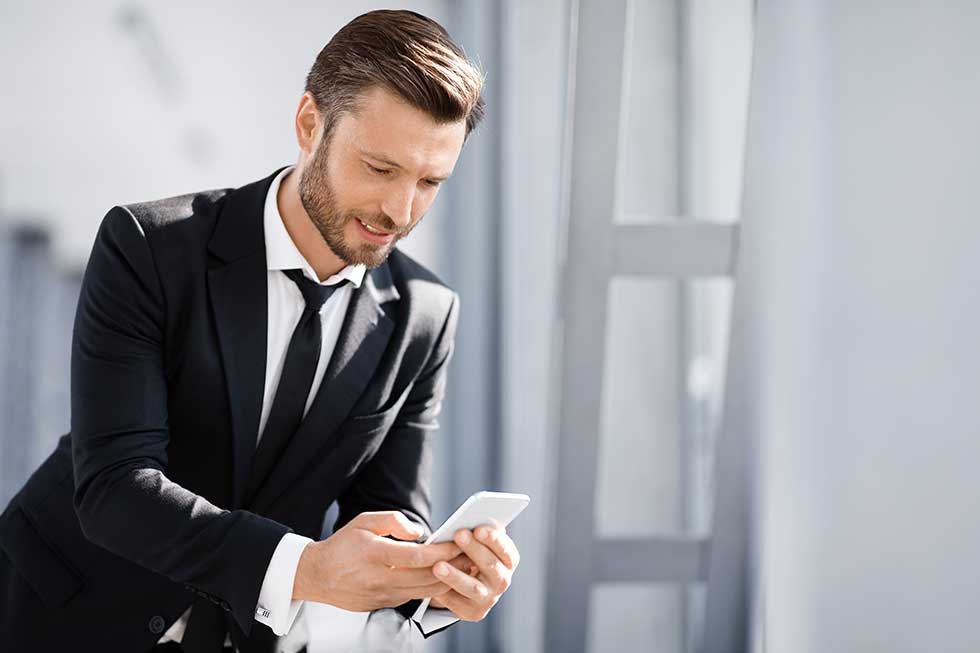 Smiling businessman texting his lover while waiting for departure